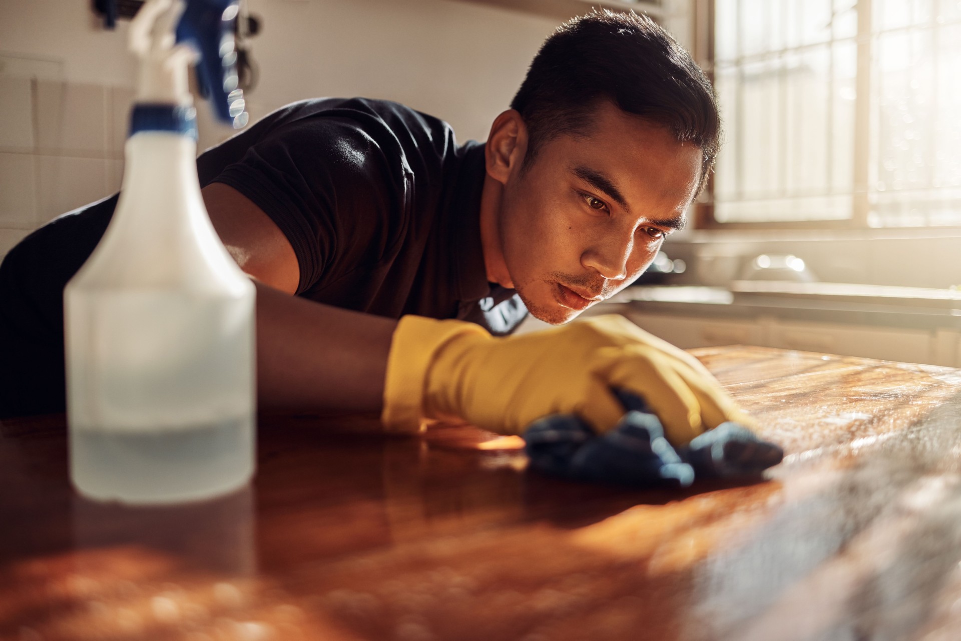 Shot of a young male professional cleaner disinfecting a kitchen counter in client's home