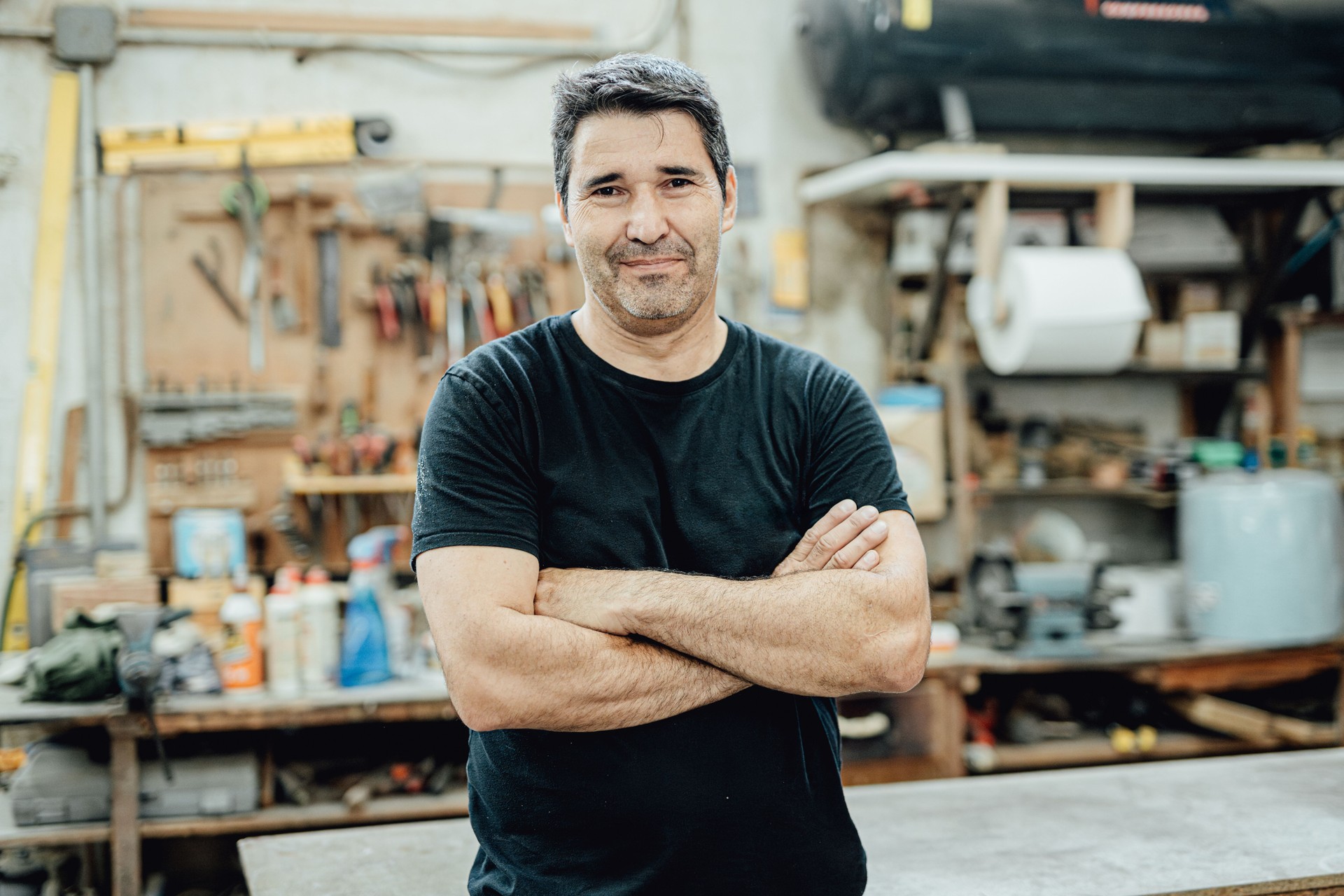 Male artisan with arms crossed standing in a woodworking shop