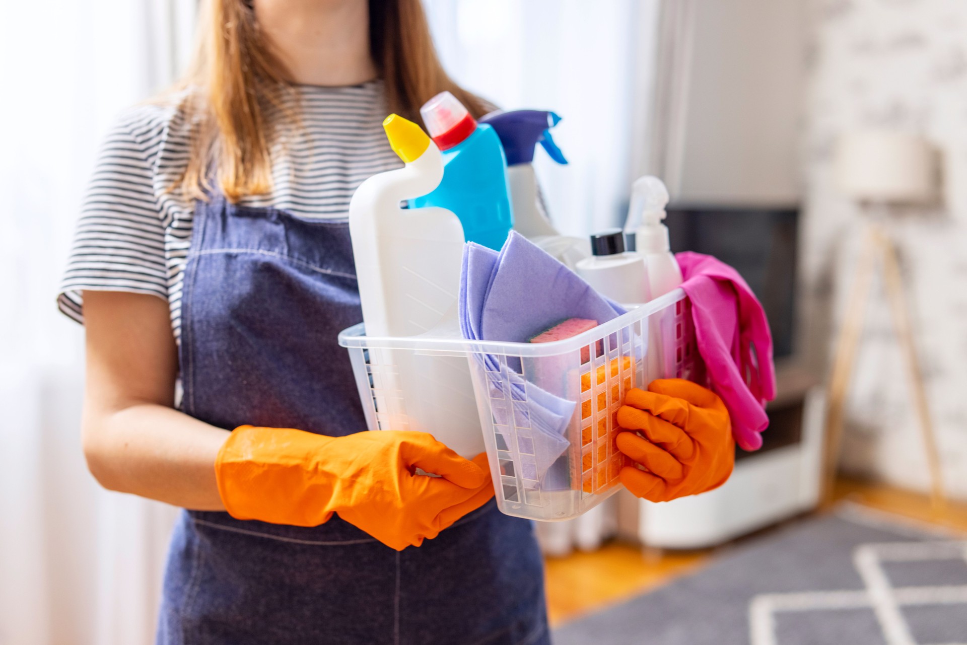 Cleaning woman in rubber gloves with basket of cleaning supplies ready to clean up